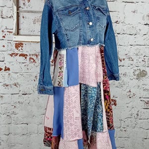 Blue denim coat with three tiers of fabric added to the bottom. Pinks, blues and brown fabrics on bottom. Hits past the knees.