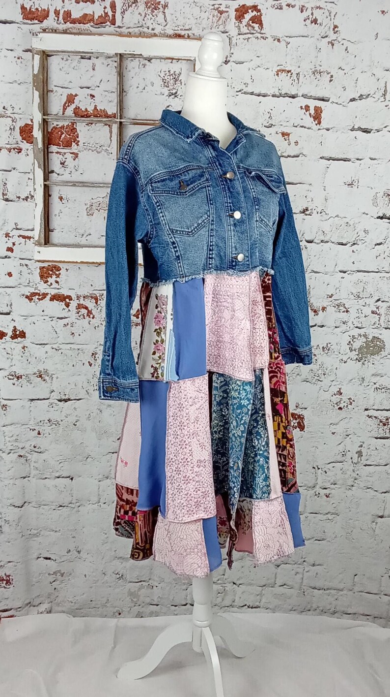 Blue denim coat with three tiers of fabric added to the bottom. Pinks, blues and brown fabrics on bottom. Hits past the knees.