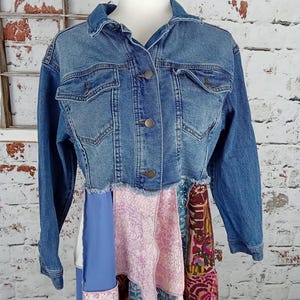 Blue denim and jean jacket buttoned up on a mannequin. Pink and blue fabric sewn to the bottom shown