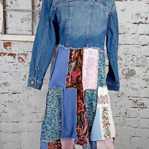 Blue denim coat with three tiers of fabric added to the bottom. Pinks, blues and brown fabrics on bottom. Hits past the knees.