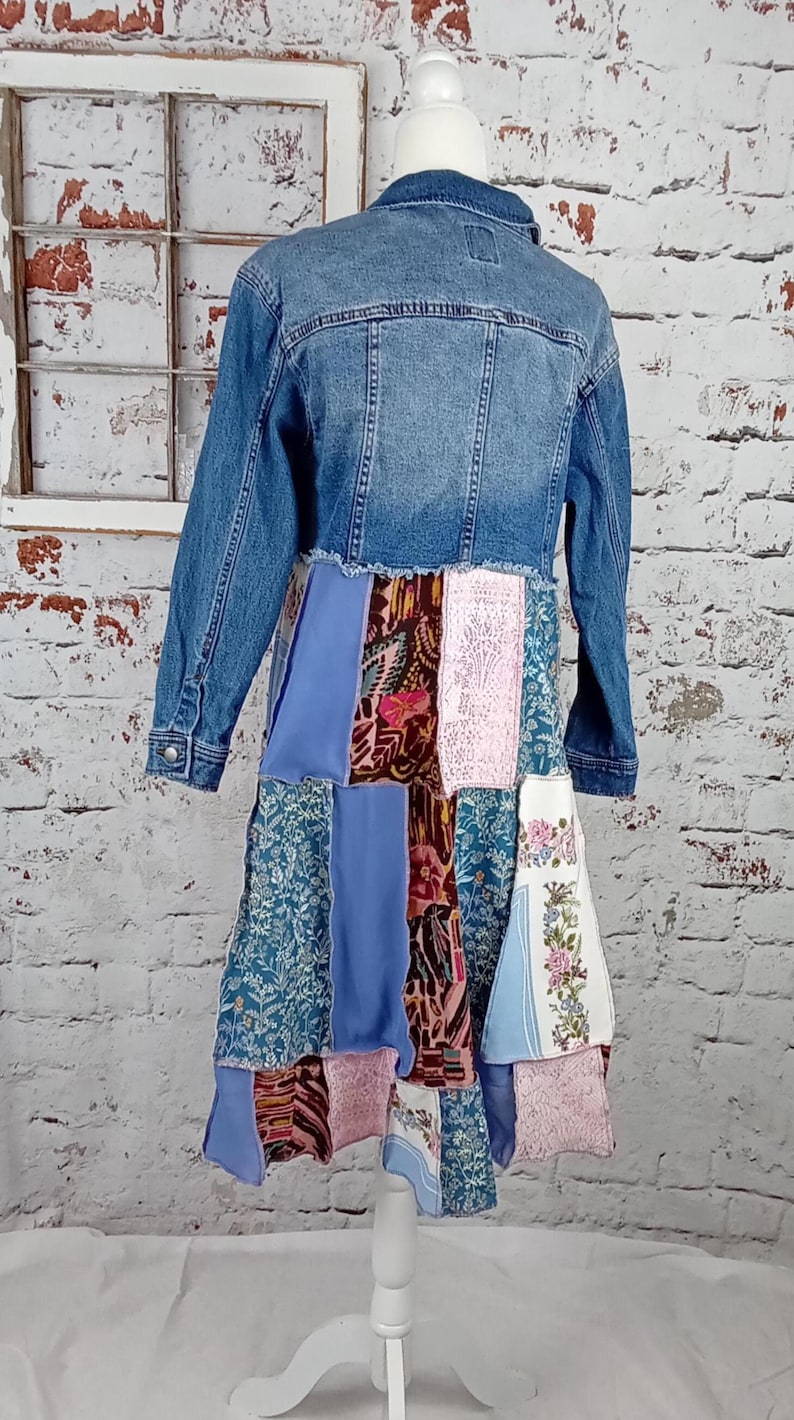 Blue denim coat with three tiers of fabric added to the bottom. Pinks, blues and brown fabrics on bottom. Hits past the knees.