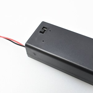 May include: A black battery holder with two wires attached. The wires are red and black. The battery holder has a small label that says "USB-C".