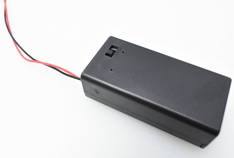 May include: A black battery holder with two wires attached. The wires are red and black. The battery holder has a small label that says "USB-C".