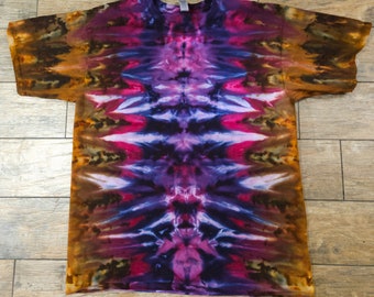 May include: A tie-dye t-shirt with a vibrant, colorful design. The shirt features a blend of purple, pink, blue, and brown hues, creating a unique and eye-catching pattern. The shirt is made of a soft material and has short sleeves and a crew neck.