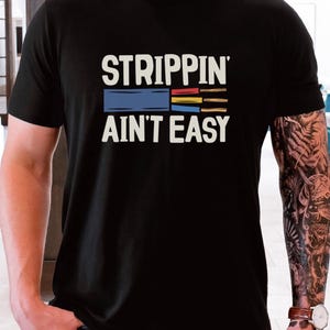 May include: Black t-shirt with the text "Strippin' Ain't Easy" and a graphic of a multi-colored electrical wire.