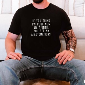 Könnte beinhalten: Ein schwarzes T-Shirt mit dem Text "If you think I'm cool now wait until you see my AI automations" in weiß gedruckt.