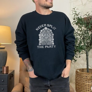 Könnte beinhalten: Schwarzes Sweatshirt mit einem weißen Aufdruck einer Steinbogen und dem Text "Never Split The Party".