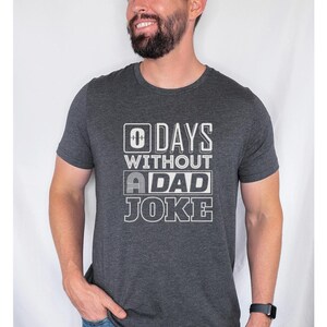 May include: Dark grey heather t-shirt with a white graphic that says "0 Days Without A Dad Joke".