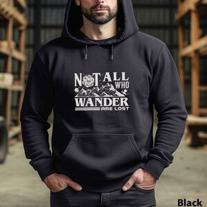 Op de afbeelding: Zwart hoodie met een witte grafische print van een 20-zijdige dobbelsteen, bergen en de tekst "Not all who wander are lost".
