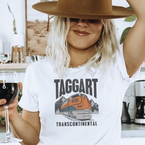 May include: White t-shirt with a graphic of a train and the text "TAGGART TRANSCONTINENTAL".