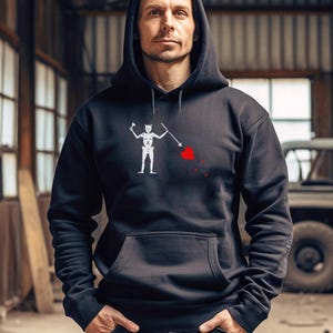 May include: A black hoodie with a white pirate skull and crossbones design. The skull is holding a heart with a red drop of blood.