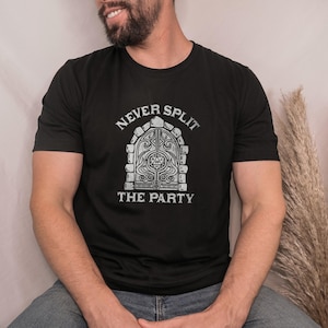 Könnte beinhalten: Schwarzes T-Shirt mit dem Text "NEVER SPLIT THE PARTY" über einer detaillierten Illustration einer Steintür. Das Shirt hat einen Rundhalsausschnitt und wird von einer Person getragen.