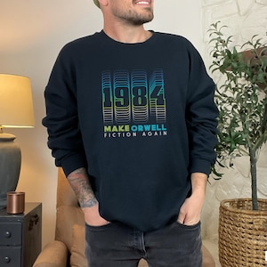 May include: Black sweatshirt with a graphic print of the number 1984 in a rainbow colour gradient. The text "Make Orwell Fiction Again" is printed below the number.