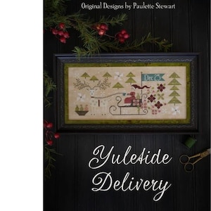 May include: A framed cross-stitch sampler titled "Yuletide Delivery" by Plum Street Samplers. The design features a reindeer-pulled sleigh with a figure, trees, and the date "Dec 25." The image has a dark background with sprigs of greenery and berries.