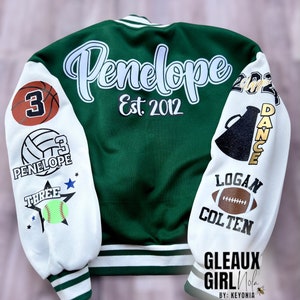 May include: Green and white varsity jacket with the name "Penelope" and the text "Est. 2012" on the back. The sleeves have various patches including a basketball, volleyball, softball, a megaphone, and a football.
