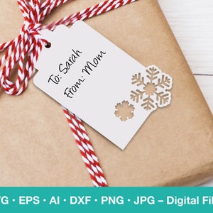 May include: A white gift tag with a snowflake design and the text "To: Sarah From: Mom". The tag is tied with a red and white striped ribbon to a brown gift box.