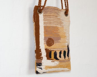 May include: A woven tapestry bag with brown straps and a geometric pattern in shades of brown, beige, and white.