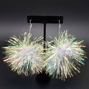 May include: A pair of iridescent silver pom-pom earrings with a silver chain and hook closure.