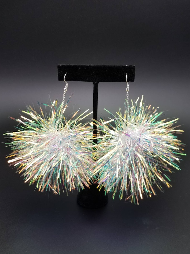 May include: A pair of iridescent silver pom-pom earrings with a silver chain and hook closure.
