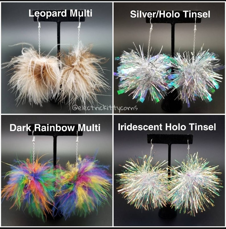 May include: Four pairs of dangle earrings with pom-pom accents. The earrings are displayed on a black stand. The pom-poms are in the following colors: leopard print, silver with iridescent holo tinsel, dark rainbow multi, and iridescent holo tinsel.