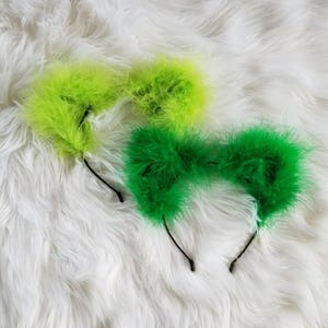 May include: Two pairs of fuzzy cat ears headbands. One pair is lime green and the other is bright green.