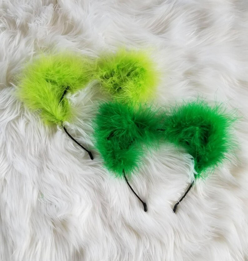 May include: Two pairs of fuzzy cat ears headbands. One pair is lime green and the other is bright green.
