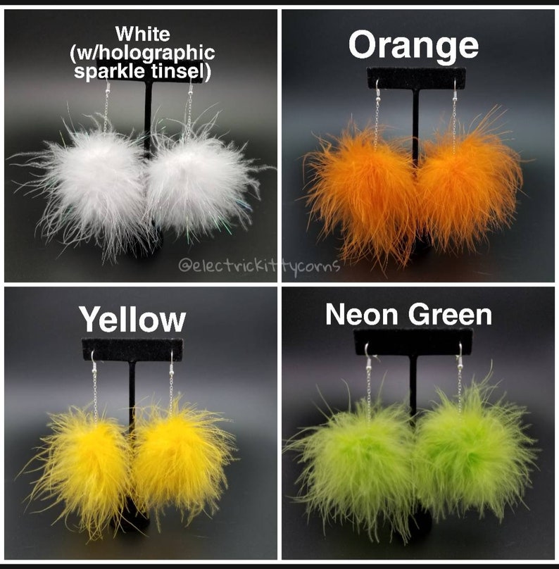 May include: Four pairs of feather earrings in different colors: white with holographic sparkle tinsel, orange, yellow, and neon green. The earrings are displayed on a black stand with silver chains.