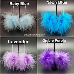 May include: Four pairs of feather earrings displayed on a black stand. The earrings are in four colors: baby blue, neon blue, lavender, and ombre purple.