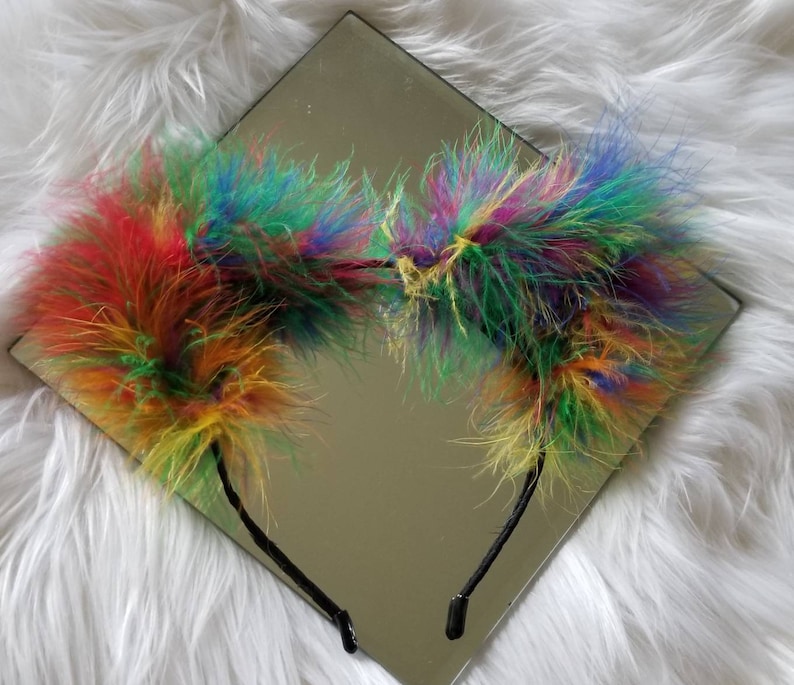 May include: A rainbow colored fluffy headband with two large pom-poms on either side.
