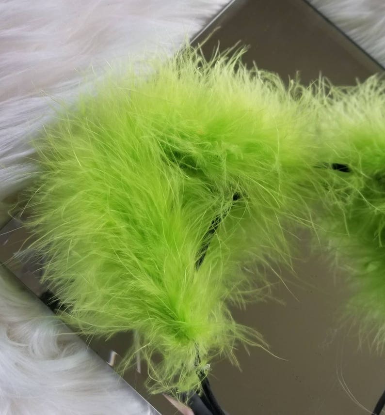 May include: A close-up of a bright green feather boa. The boa is soft and fluffy, and it is perfect for adding a touch of fun and whimsy to any outfit.
