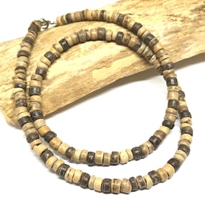 May include: A brown and beige wooden bead necklace with a silver clasp. The necklace is made of small, round beads that are strung together on a thin cord.