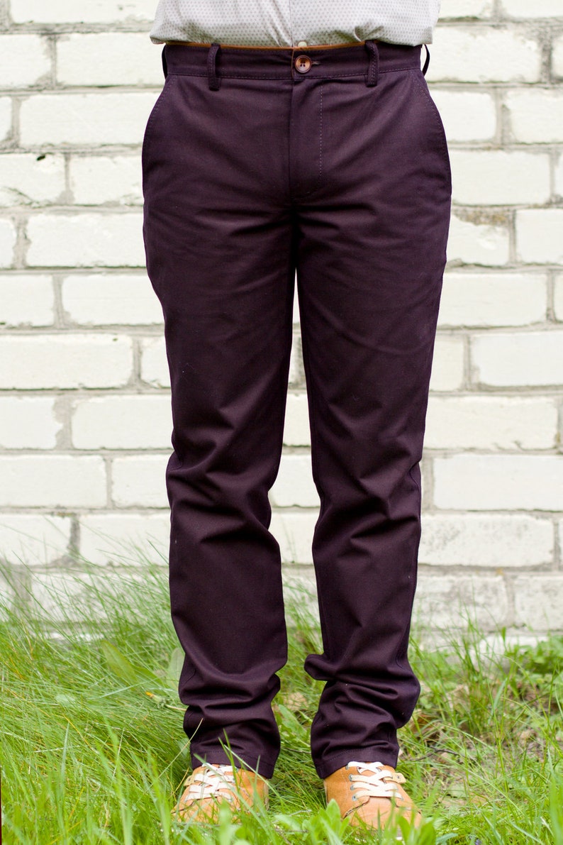 May include: A pair of dark purple pants with a brown belt and a white button.