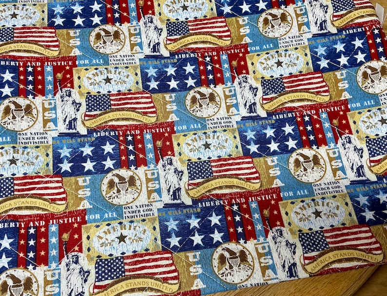 Pu&ograve; includere: Un tessuto patriottico con motivi ripetuti della bandiera americana, della Statua della Libert&agrave; e delle frasi "America Stands United" e "Liberty and Justice for All". Il design utilizza i colori rosso, bianco e blu.