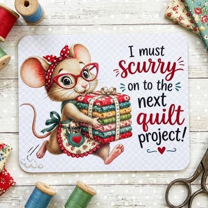 May include: A rectangular mouse pad featuring a cartoon mouse wearing red glasses and a polka dot headband, holding a stack of colorful fabric squares. The text reads, I must scurry on to the next quilt project! The design includes a small red heart.