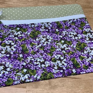 Puede incluir: Una bolsa con cremallera de color morado y verde con estampado floral. La bolsa est&aacute; acolchada y tiene un forro de lunares verde claro.