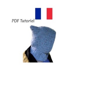 Puede incluir: Una capucha de punto azul claro, posiblemente un pasamontañas o un cuello, es usada por una persona. El texto "PDF Tutoriel" está encima de la capucha, con la bandera francesa en el fondo. La capucha parece hecha a mano.