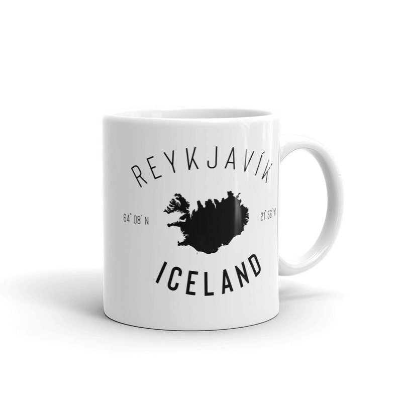 May include: White ceramic mug with a black graphic of Iceland and the text "REYKJAVIK" and "ICELAND". The graphic also includes the coordinates "64&deg; 08' N" and "21&deg; 56' W".