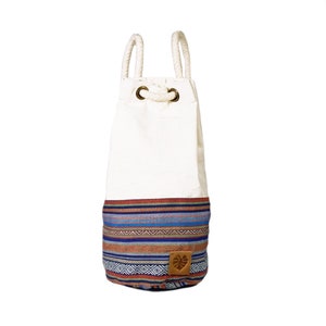 May include: White canvas drawstring bag with a blue, red and brown patterned bottom. The bag has a leather patch with a leaf design.