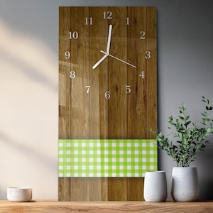 May include: A rectangular wall clock with a wooden background and white hands. The clock face features silver numerals and a green and white checkered pattern at the bottom. The clock is approximately 12 inches wide and 24 inches tall.