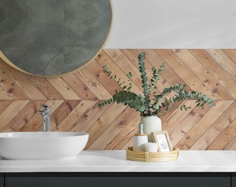 May include: A modern bathroom vanity with a white countertop, a white oval sink, and a chrome faucet. A woven tray holds a soap dispenser, soap, and a framed picture. The background features a wooden plank wall and a round mirror.