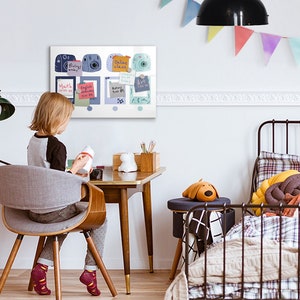 May include: A white magnetic board with colorful sticky notes and illustrations of cameras. The board is hanging on a white wall in a child's bedroom. A child is sitting at a desk in front of the board.