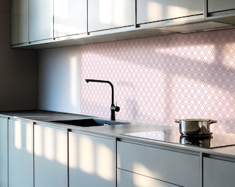 May include: A modern kitchen with gray cabinets and a pink patterned backsplash. A black faucet is mounted above a stainless steel sink. A black electric stovetop is visible in the foreground.