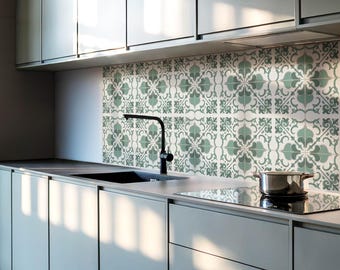 May include: A modern kitchen with white cabinets and a stainless steel stovetop. The backsplash is a green and white patterned tile.