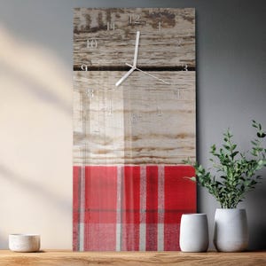 May include: A rectangular wall clock with a rustic wood grain top and a red and white plaid pattern at the bottom. The clock face has silver numerals and hands. The clock is displayed on a wooden shelf with decorative items.