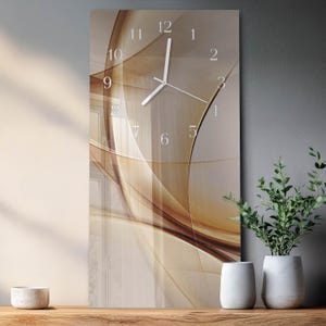 May include: A rectangular wall clock featuring a smooth glass surface with an abstract design of flowing, translucent amber and brown curves. The clock face displays white Arabic numerals from one to twelve and thin white hour and minute hands.