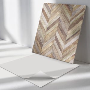May include: A sheet of peel and stick wallpaper with a herringbone pattern in shades of brown, beige, and gray. The wallpaper is shown with the backing peeled back to reveal the adhesive.