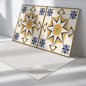 Peut inclure: Deux carreaux carrés avec un motif géométrique. Les carreaux sont de couleur crème avec une étoile jaune au centre. L'étoile a un contour bleu et des pointes bleues. L'arrière-plan des carreaux est de couleur crème avec un motif géométrique bleu et jaune.