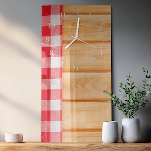May include: A rectangular wall clock with a light wood grain background and silver-colored numerals. A red and white checkered pattern is on the left side. The clock hands are silver. The clock is approximately 12 inches wide and 24 inches tall.