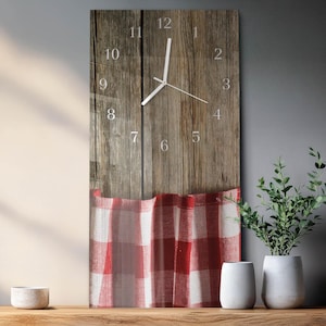 May include: A rectangular wall clock with a wooden background and a red and white checkered pattern at the bottom. The clock face has silver numerals and hands. The clock is displayed on a wooden surface with decorative plants.