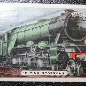 May include: A green and black steam locomotive train with red passenger cars. The train is labeled "Flying Scotsman" and "LNER 2518".